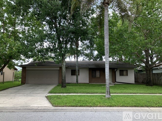A house with a garage and a tree in front.