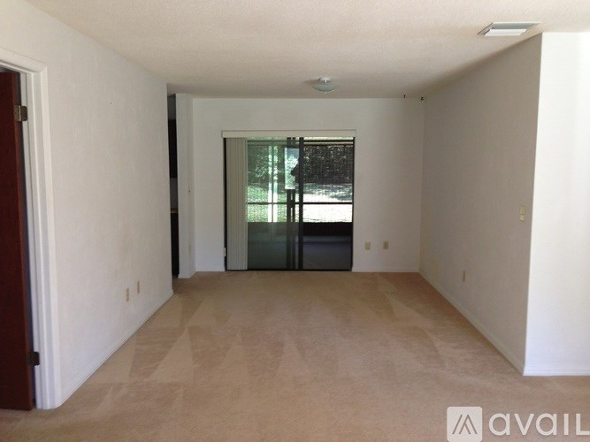 A room with a carpeted floor and a sliding glass door leading to a backyard.