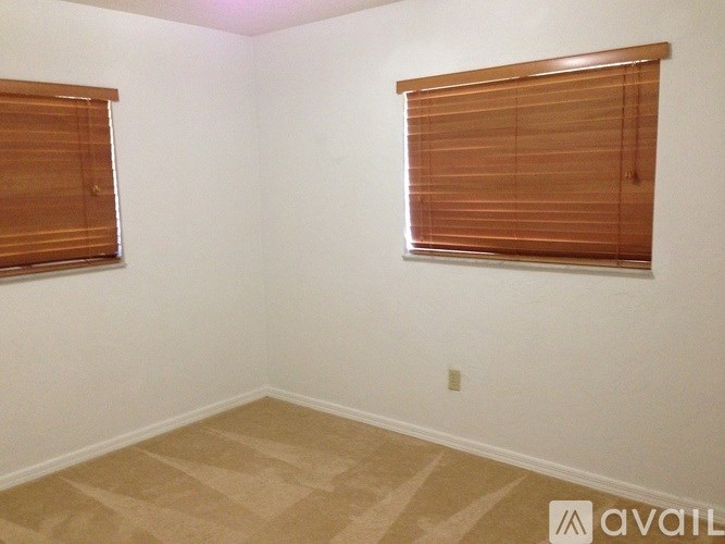 A room with a window covered by wooden blinds.