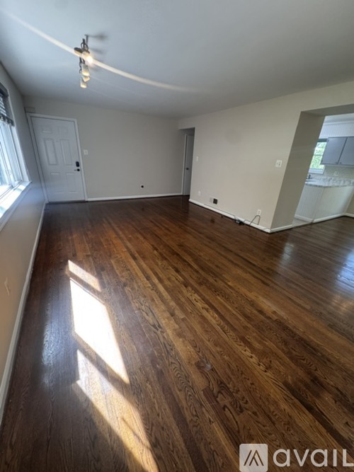 A room with wooden flooring and a door in the background.