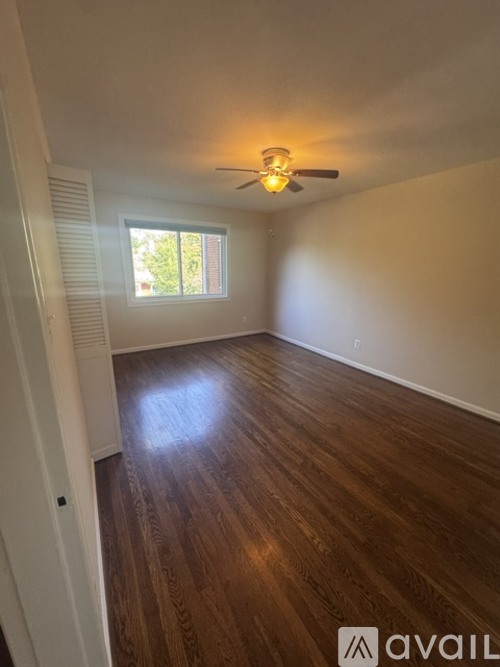 A spacious room with wooden flooring and a window.