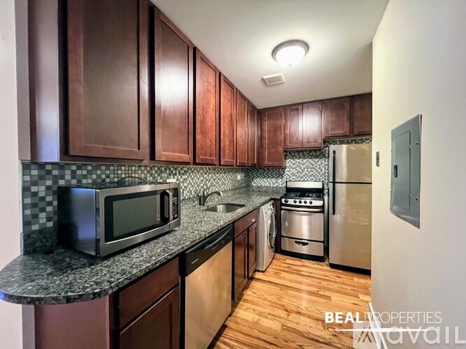 A kitchen with dark wood cabinets and a granite countertop.