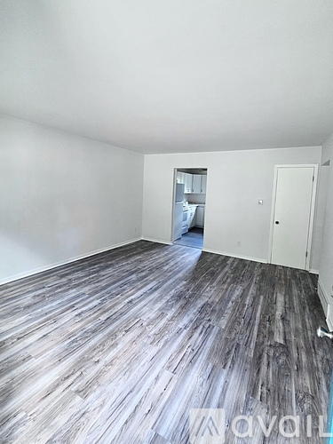 A room with wooden flooring and white walls.