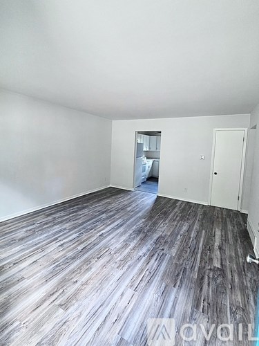 A room with wooden flooring and white walls.