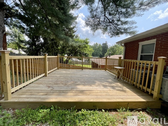 A wooden deck with a bench and a table is surrounded by a fence and trees.
