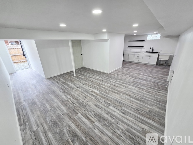 A spacious room with wooden flooring and white walls.