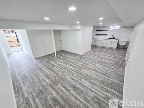 A spacious room with wooden flooring and white walls.