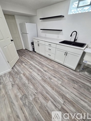 A kitchen with white cabinets and a wooden floor.