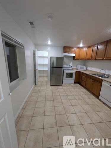 A kitchen with tile flooring and wooden cabinets.