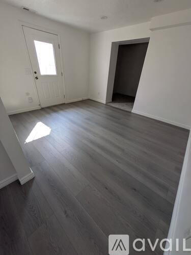 A room with wooden flooring and a door on the left side.