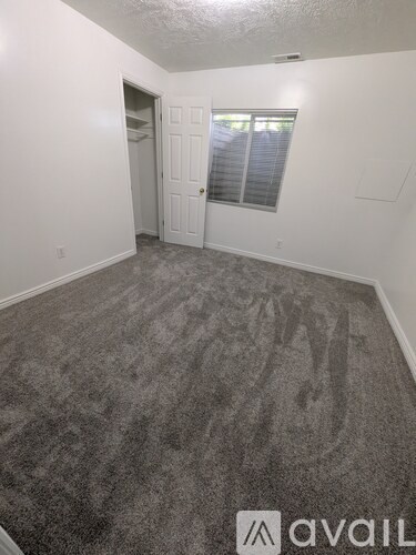 A carpeted room with a door and a window.