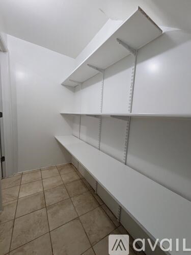 Empty white shelves in a room with tiled floor.