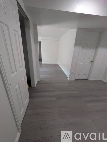 A hallway with white doors and grey flooring.