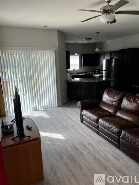 A living room with a brown leather couch and a television on a wooden stand.