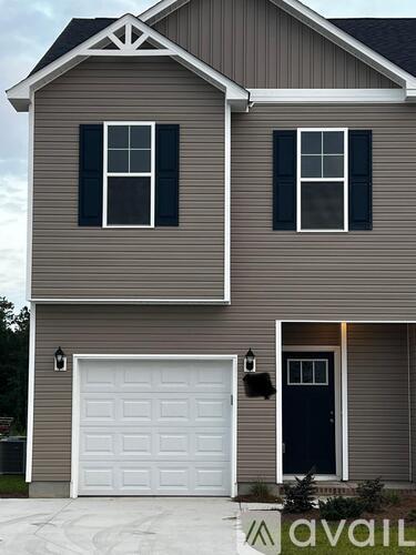 A two-story house with a white garage door and a black front door.