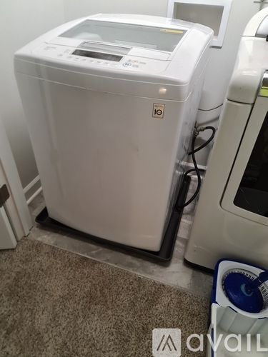 A white washing machine is in a room with a carpeted floor.