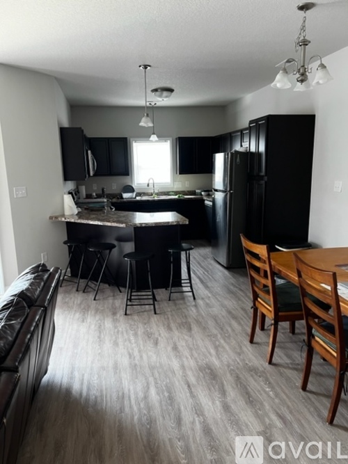 A kitchen with black cabinets and a wooden table.