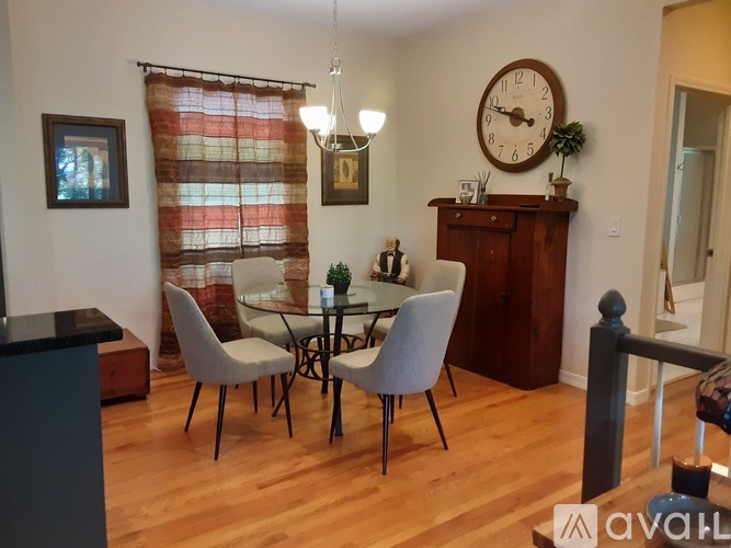 A dining room with a table set for two and a clock on the wall.