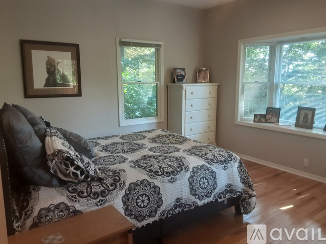 A bedroom with a bed, dresser, and picture frames on the windowsill.