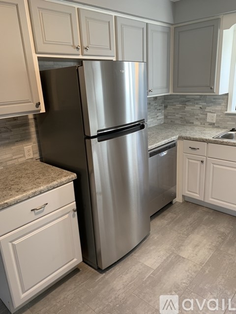 A stainless steel refrigerator in a kitchen with white cabinets.