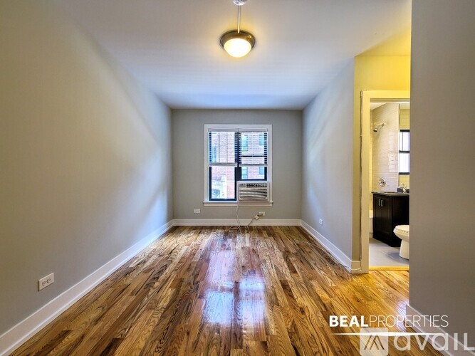 A room with wooden floors and a window with blinds.