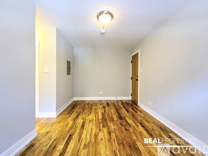 A room with wooden flooring and white walls, with a light on the ceiling and a door on the right.