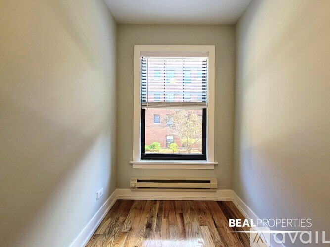 A room with a window showing a view of a tree and a building outside.