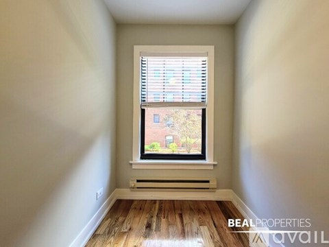 A room with a window showing a view of a tree and a building outside.