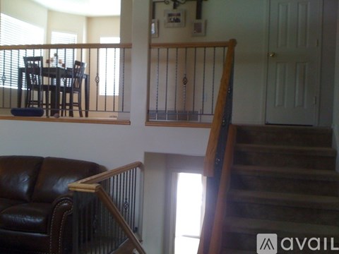 A living room with a brown leather couch and a dining table with chairs.