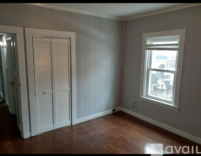A room with a window and a wooden floor.