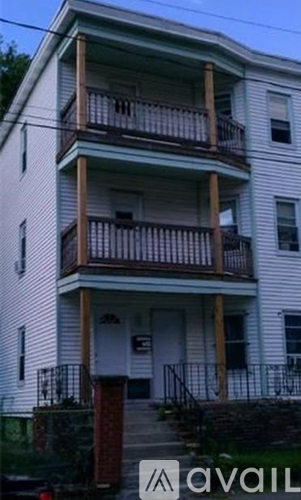 A white two-story apartment building with a balcony on the second floor.