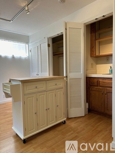 A kitchen with a white cabinet and wooden floors.
