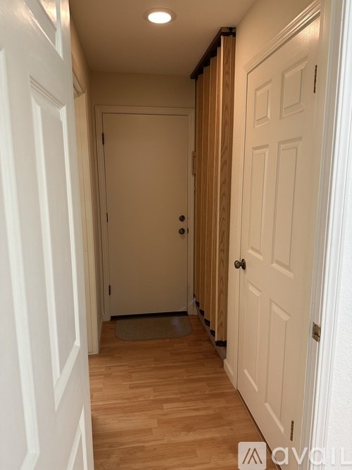 A hallway with white doors and wooden floors.