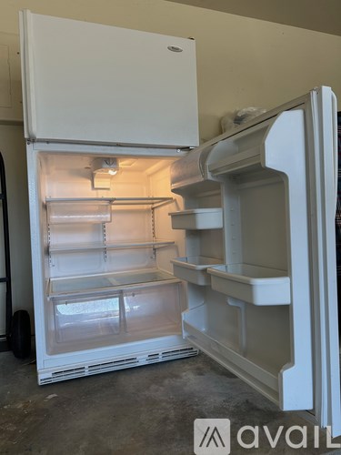 A white refrigerator with the door open is in a room.