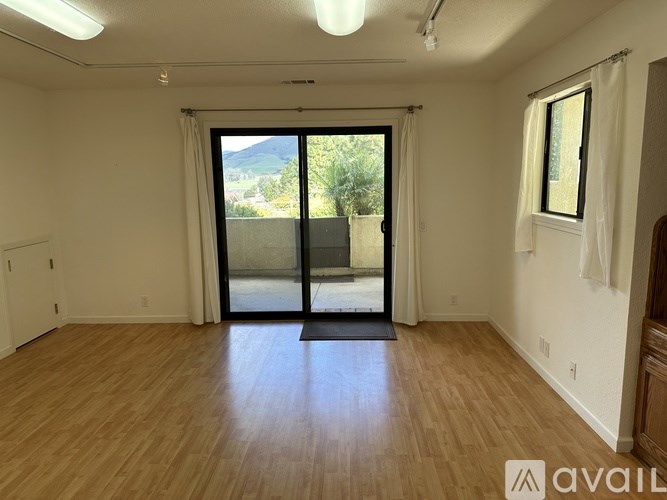 A room with wooden flooring and a sliding glass door leading outside.