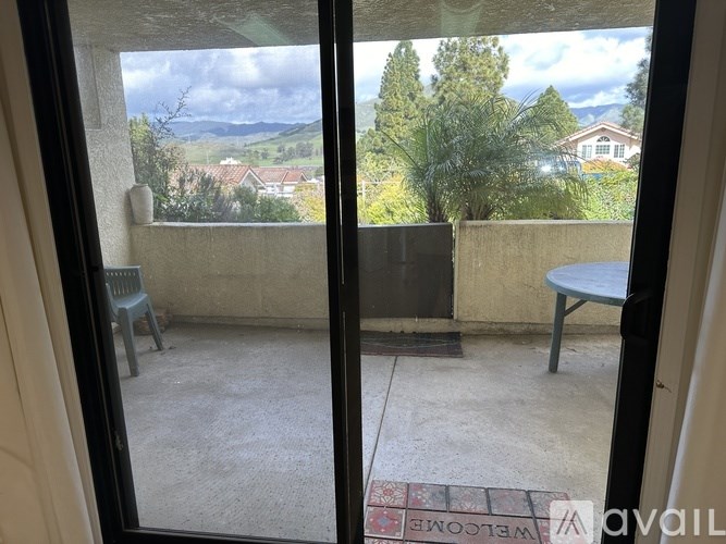 A balcony with a table and a chair is visible through a glass door.