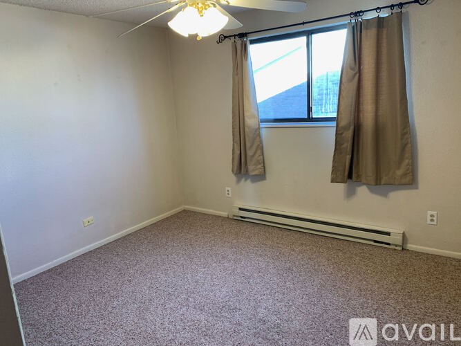 A room with a window and a fan on the ceiling.