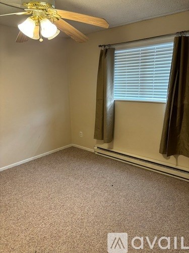 A room with a ceiling fan and carpeted floor.