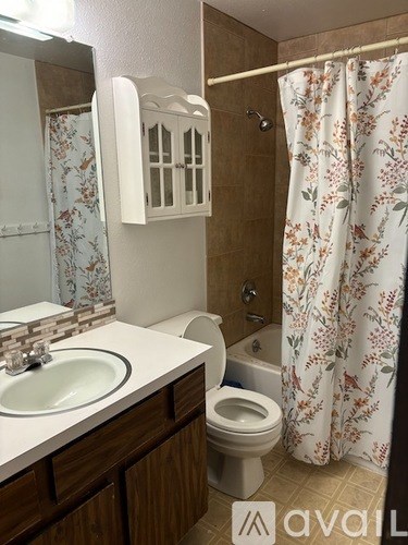 A bathroom with a floral shower curtain and a white sink.