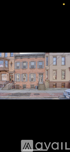 A row of brown and beige houses with a car parked in front of the first house.