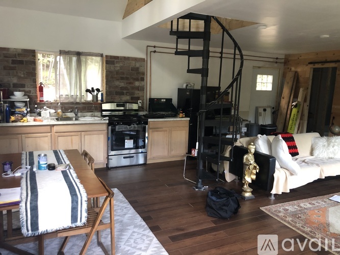 A living room with a spiral staircase and a kitchen area.