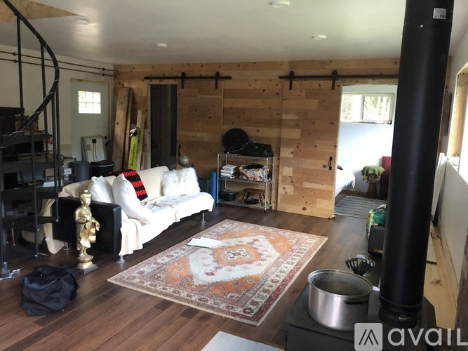 A living room with a white couch and a rug on the floor.