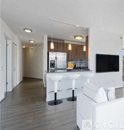 A modern living room with a kitchen area in the background.