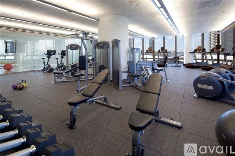 A gym with a variety of equipment including dumbbells, weight plates, and a bench press.