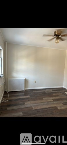 A room with a ceiling fan and wooden flooring.