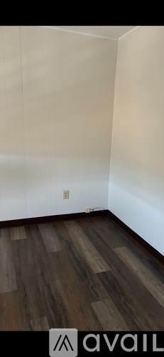 A room with wooden flooring and white walls.