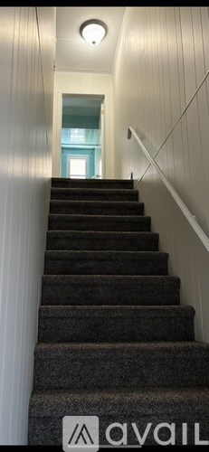 A staircase with a carpeted runner and white walls.
