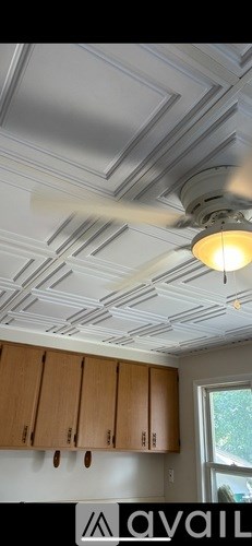 A kitchen with wooden cabinets and a ceiling fan.
