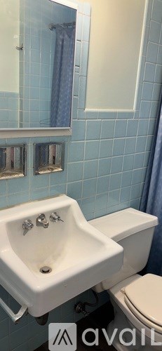 A white sink with two faucets is in a bathroom with blue tiles.