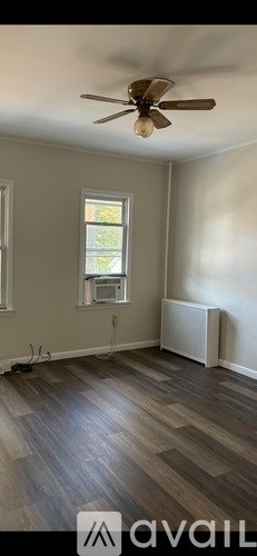A room with a ceiling fan and a window with a view of trees.